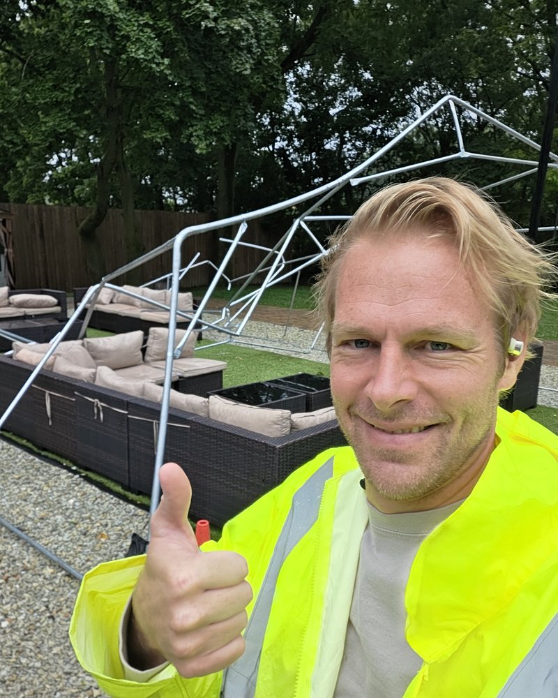 Jared in hi-vis holding a mangled gazebo frame